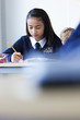 Photo: Female student in school uniform taking exam at desk in classroom Female student in school uniform taking exam at desk in classroom