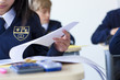 Photo: Students in school uniforms taking exam at desks in classroom Students in school uniforms taking exam at desks in classroom