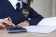 Photo: Female student in school uniform using calculator for exam at desk in classroom Female student in school uniform using calculator for exam at desk in classroom