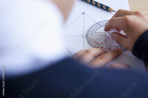Photo: Male student using protractor at desk Male student using protractor at desk