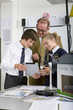 Foto: Teacher and students in school uniforms using digital tablet next to wind turbine model in science class Teacher and students in school uniforms using digital tablet next to wind turbine model in science class