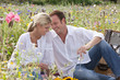 Smiling couple drinking white wine and picnicking in sunny wildflower field