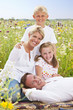 Portrait of smiling family relaxing in sunny wildflower field