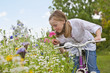 Girl on bicycle smelling wildflower in field