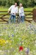 Couple with bicycles pointing in wildflower field