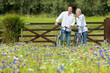 Couple with bicycles pointing in wildflower field