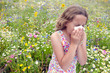 Girl standing in field of wildflowers blowing her nose