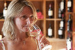 Woman smelling white wine in wine shop