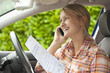 Smiling woman in car holding certificate and talking on cell phone