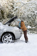 Photo: Woman standing in snow checking underneath carճ hood Woman standing in snow checking underneath carճ hood