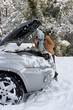 Photo: Woman standing in snow checking underneath carճ hood and talking on cell phone Woman standing in snow checking underneath carճ hood and talking on cell phone