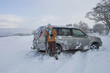 Photo: Woman standing in snow with skidded car talking on cell phone Woman standing in snow with skidded car talking on cell phone