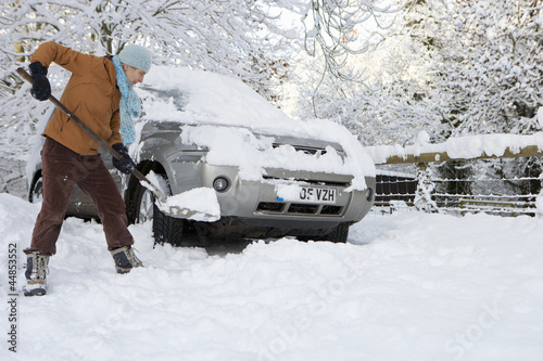 Photo: Woman shoveling snow near car Woman shoveling snow near car
