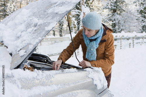 Photo: Woman standing in snow checking underneath carճ hood Woman standing in snow checking underneath carճ hood