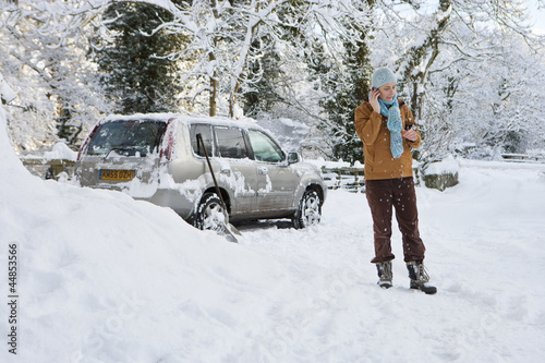 Photo: Woman standing in snow near car talking on cell phone Woman standing in snow near car talking on cell phone