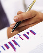 Photo: Close up of businessman holding pen near bar graph Close up of businessman holding pen near bar graph