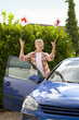 Smiling young woman throwing learnerճ permit sticker in air next to car