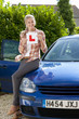 Photo: Portrait of smiling young woman holding learnerճ permit sticker on hood of car Portrait of smiling young woman holding learnerճ permit sticker on hood of car