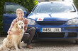 Foto: Portrait of smiling young woman with dog in front of car with learnerճ permit Portrait of smiling young woman with dog in front of car with learnerճ permit