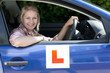 Portrait of smiling young woman driving car with learnerճ permit sticker