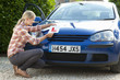 Young woman attaching learnerճ permit sticker to car