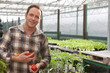 Portrait of smiling man holding tomatoes in greenhouse