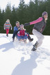 Happy family sledding in snow