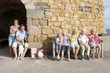 Portrait of family with dog sitting in front of stone building