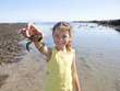 Smiling girl holding small crab on sunny beach