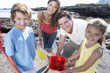 Portrait of smiling family holding pail with starfish on sunny beach