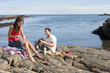 Couple picnicking on rocks along ocean