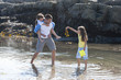 Father and daughters wading in tide pool