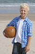 Portrait of smiling boy holding soccer ball on sunny beach