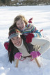 Foto: Portrait of smiling mother and daughter laying on sled in snow Portrait of smiling mother and daughter laying on sled in snow
