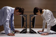 Businessman and businesswoman leaning on computers in office