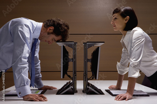 Photo: Businesswoman watching businessman lean on computer in office Businesswoman watching businessman lean on computer in office
