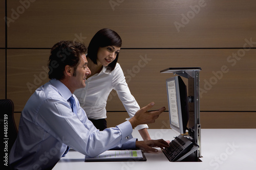 Photo: Businessman and businesswoman working at computer in office Businessman and businesswoman working at computer in office