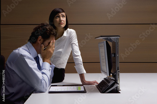 Photo: Worried businessman and businesswoman working at desk in office Worried businessman and businesswoman working at desk in office