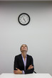 Foto: Businesswoman looking up at clock in office Businesswoman looking up at clock in office