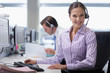 Portrait of smiling businesswoman wearing headset at desk in office