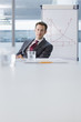 Photo: Portrait of confident businessman sitting near chart in conference room Portrait of confident businessman sitting near chart in conference room