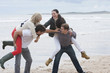 Young couples in piggyback battle on beach