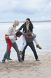 Young couples in piggyback battle on beach