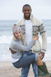 Portrait of young woman hanging from boyfriend on beach