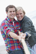 Portrait of smiling young couple playing tug-of war