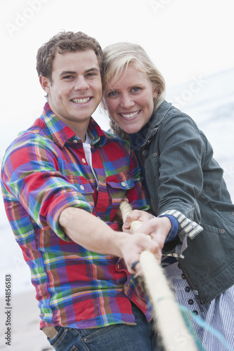 Photo: Portrait of smiling young couple playing tug-of war Portrait of smiling young couple playing tug-of war