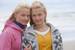 Portrait of smiling teenage twin sisters on beach