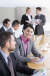 Foto: Portrait of confident businesswoman holding report among co-workers in conference room Portrait of confident businesswoman holding report among co-workers in conference room