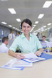 Portrait of smiling businesswoman wearing headset and reviewing report in office