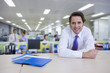 Portrait of confident businessman leaning on cabinet in office